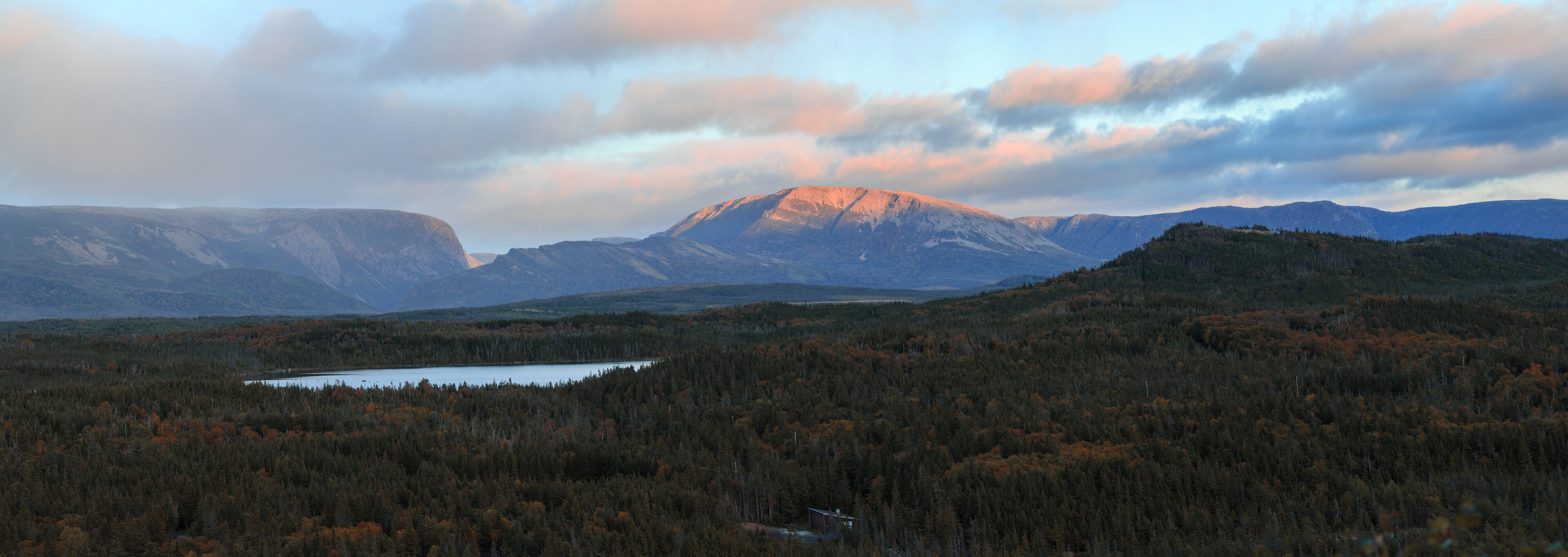 A mountainous landscape with a lake and dense forest.