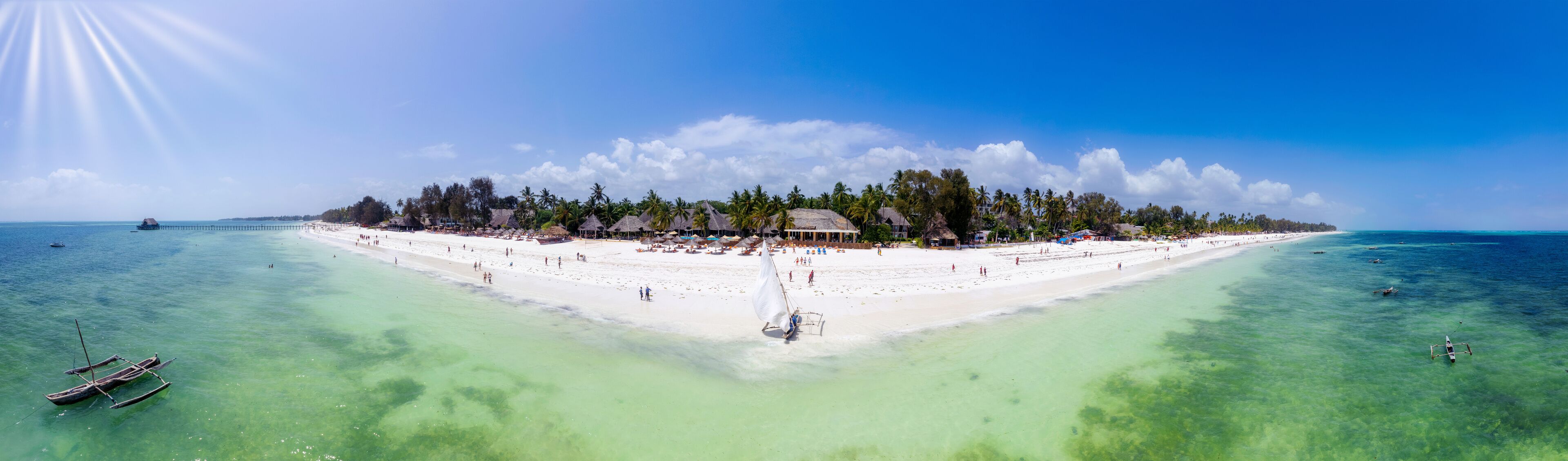 A tropical island with a white sandy beach, clear turquoise waters, and a thatched-roof structure.