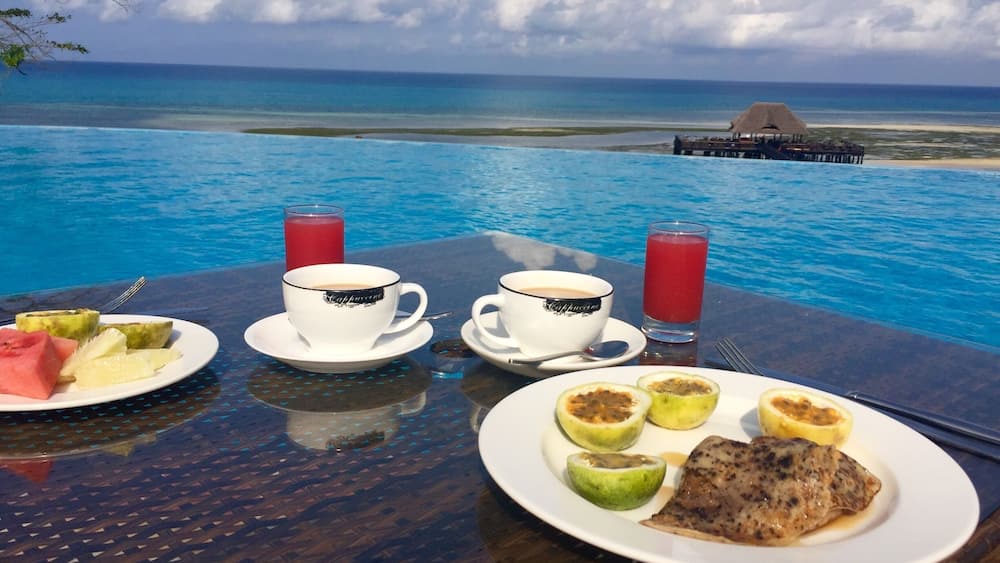 Ein Tisch mit Frühstück, mit Blick auf den Ozean und einem Pool.