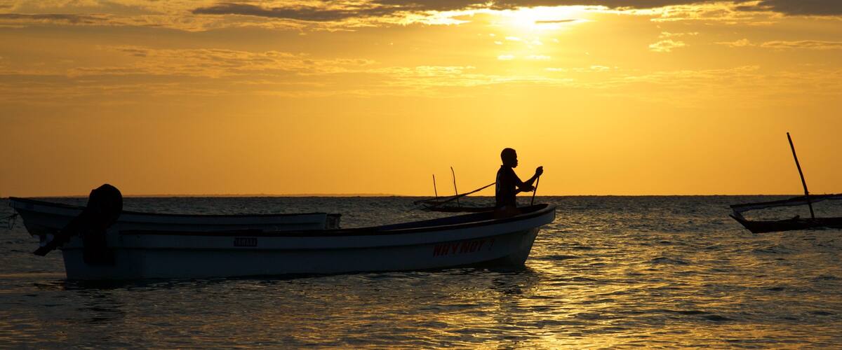 A sunset over the ocean with two boats.