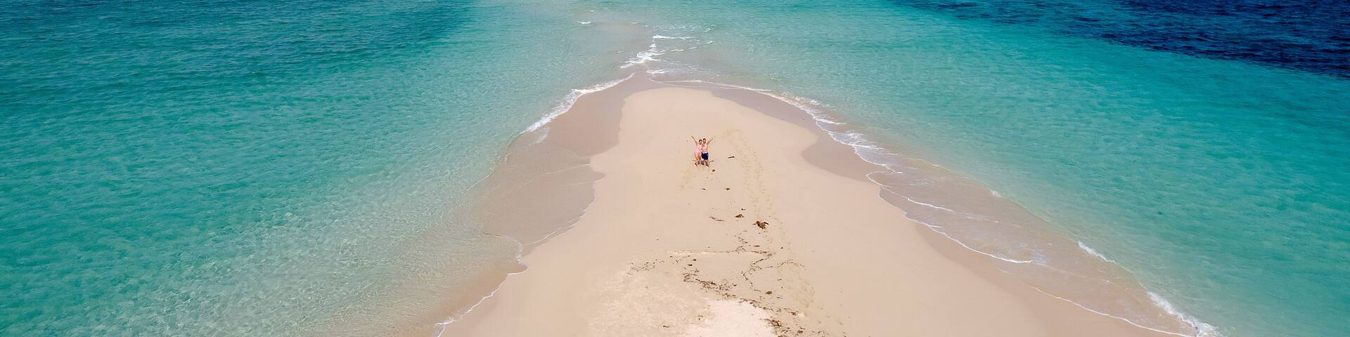 A beach with clear turquoise waters and a sandy shore.