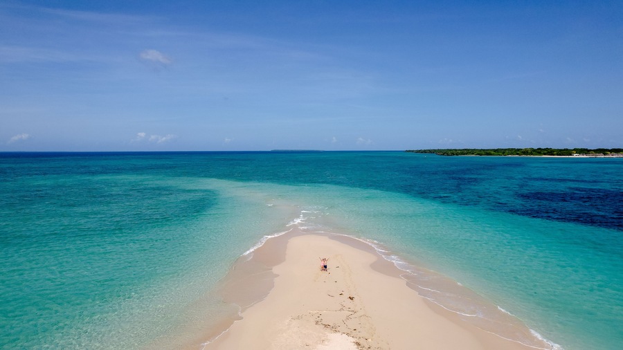 A beach with clear turquoise waters and a sandy shore.