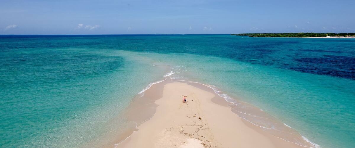 A beach with clear turquoise waters and a sandy shore.