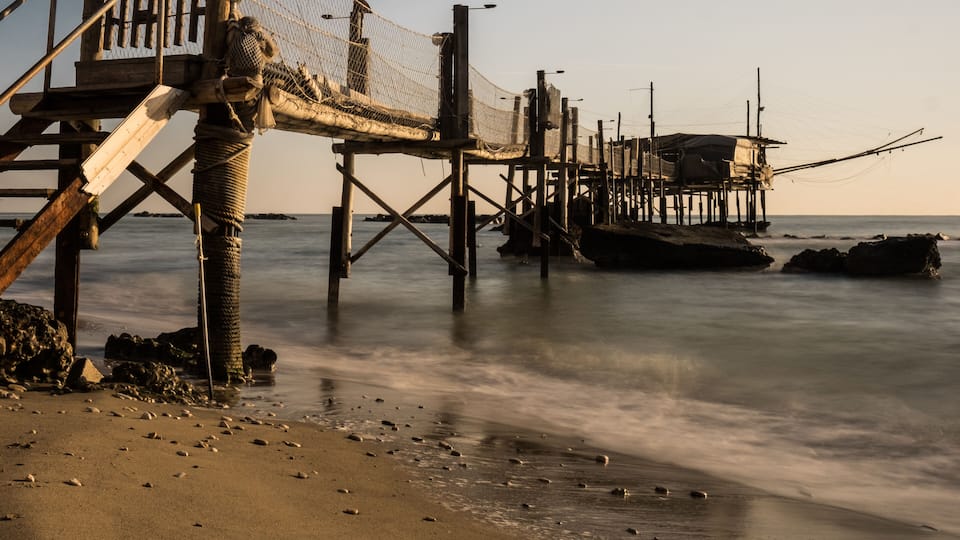 A wooden pier with fishing nets extending into calm waters.