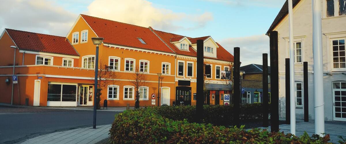 A historic building with a red-tiled roof, a white facade, and a large central window.