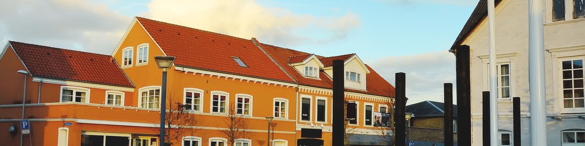 A historic building with a red-tiled roof, a white facade, and a large central window.
