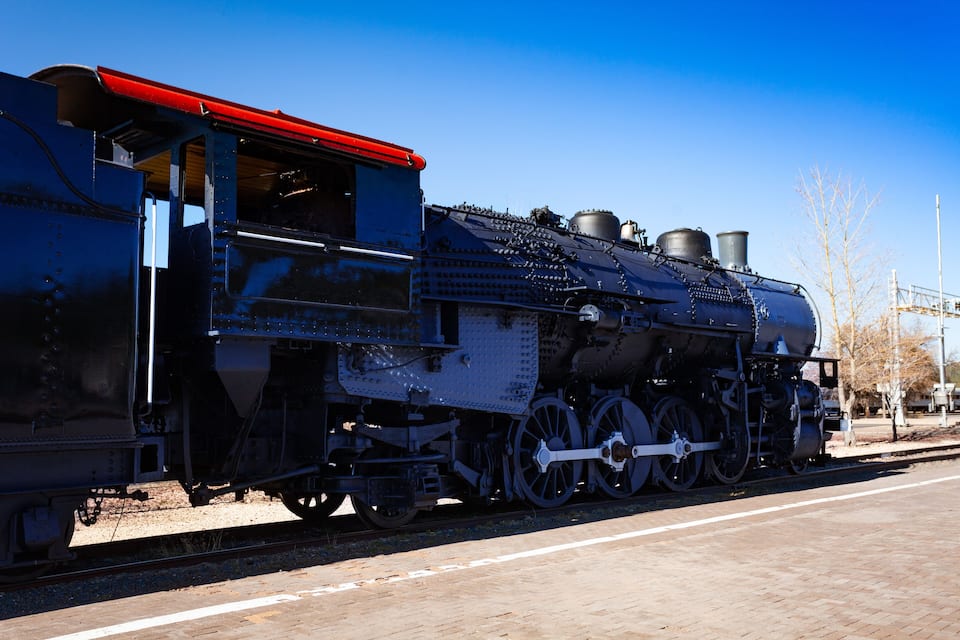A steam locomotive with a red roof and black body, parked on a track.