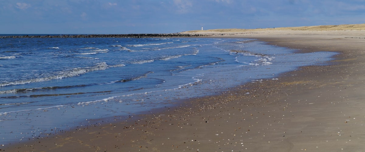 A sandy beach with gentle waves and a clear blue sky.