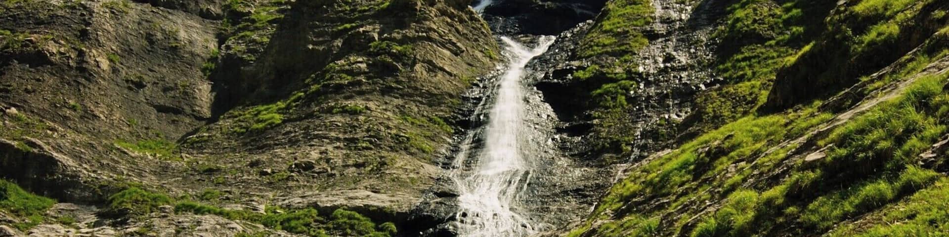 A waterfall cascading down a rocky hillside with lush greenery.