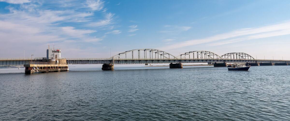 A bridge over a river with a boat in the foreground.