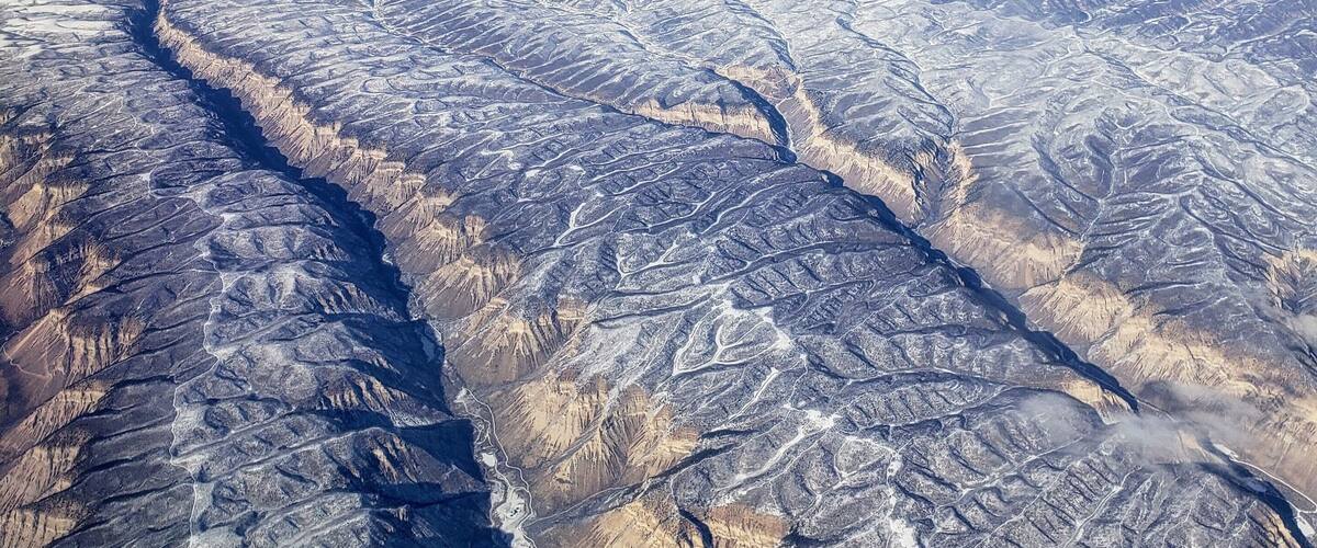 A vast mountainous landscape with snow-covered peaks and valleys.