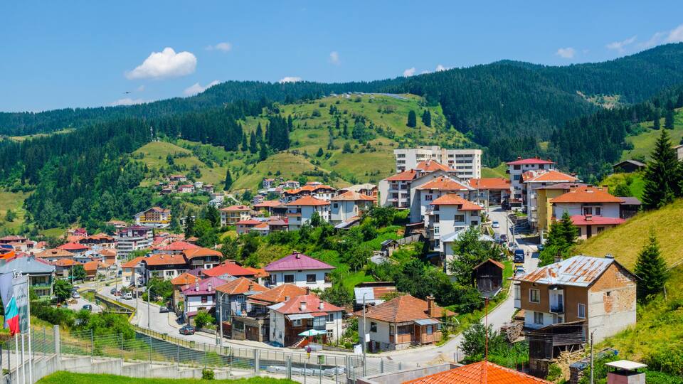 A hillside village with terraced houses and a flag.