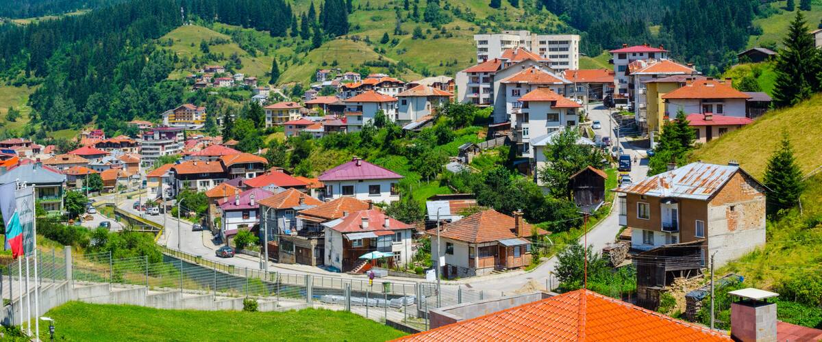 A hillside village with terraced houses and a flag.