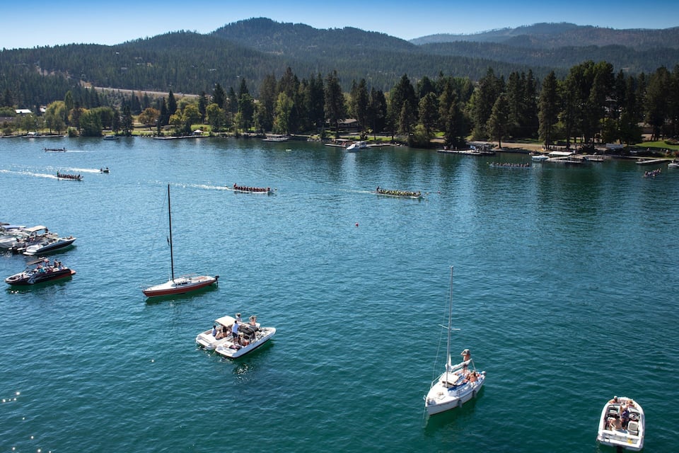 A lake with several boats and a forested mountain range in the background.