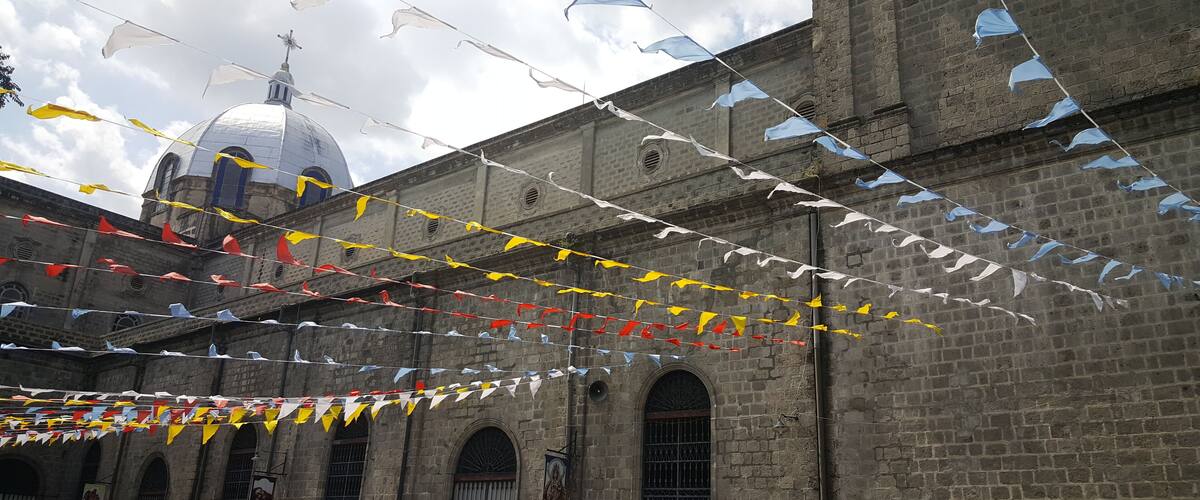 A historic building with a dome and arched windows, decorated with multicolored flags.