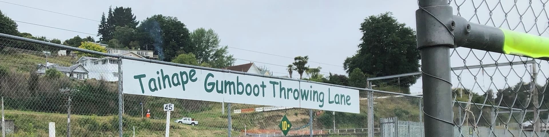 A fenced area with a sign reading "Taihape Gumboot Throwing Lane" and a stone wall in the background.