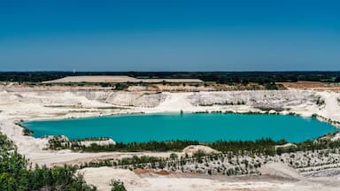 A large turquoise lake surrounded by white rock formations and sparse vegetation.