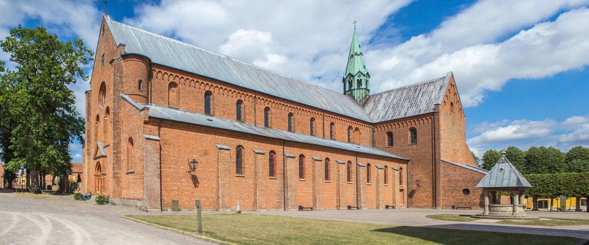 A large brick church with a tall spire and a bell tower.