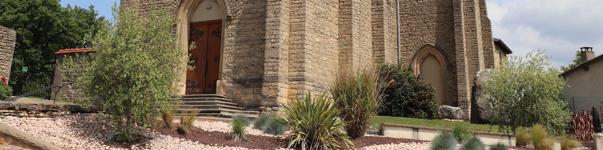A stone church with a large circular window and a cross on top.