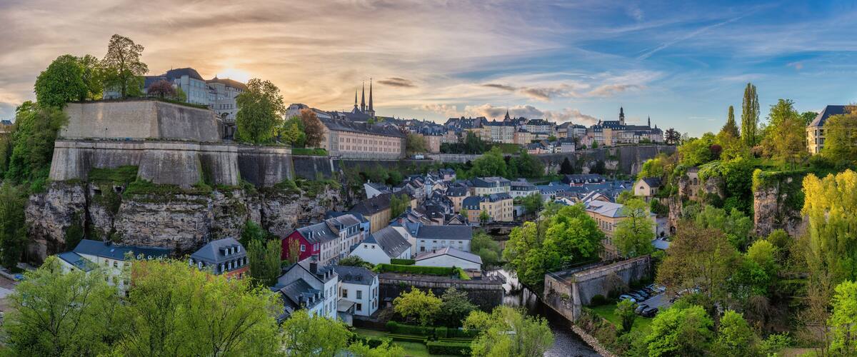 A historic town with a river, stone fortifications, and a prominent church spire.