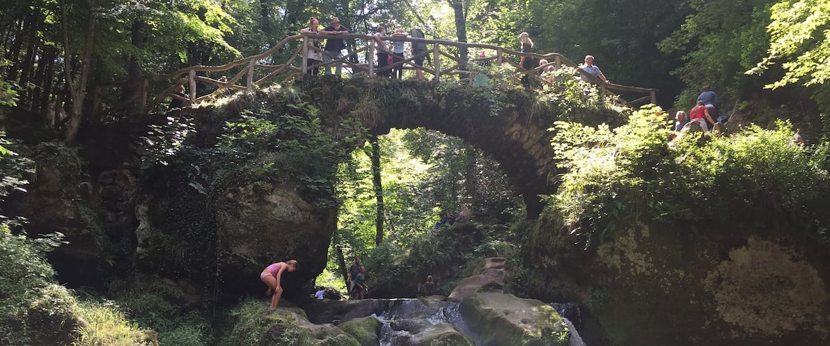 Un ponte di legno sopra una cascata in una zona boschiva.