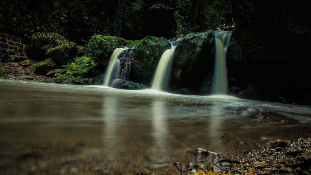 Ein Wasserfall mit zahlreichen Bächen, die über moosbewachsene Felsen fließen.
