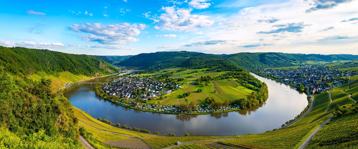 A river winding through a valley with a town on one side and hills on the other.