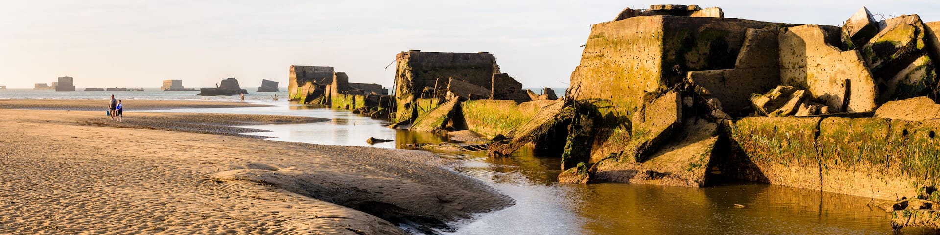 A sandy beach with water channels and large rock formations.