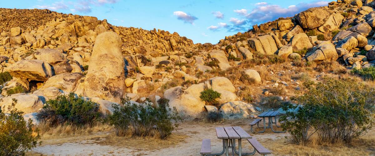 A rocky desert landscape with a picnic table and grill.