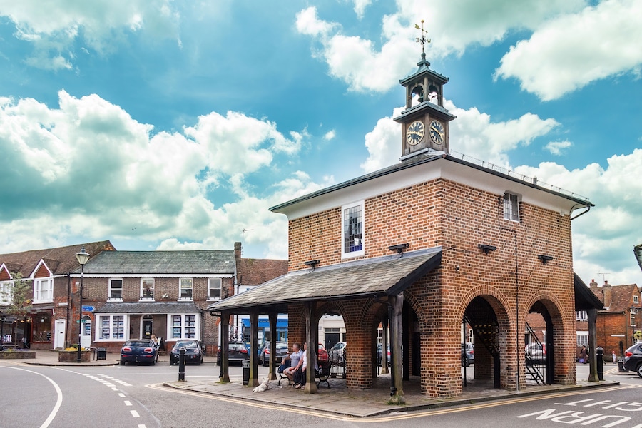 A brick building with a clock tower and a covered waiting area.