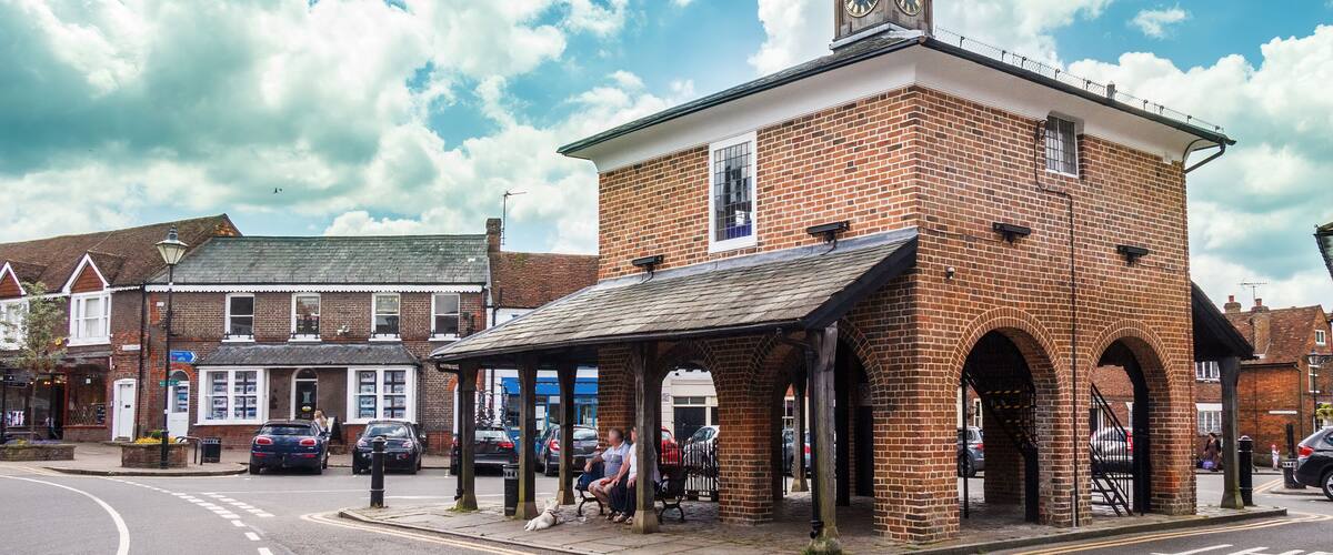 A brick building with a clock tower and a covered waiting area.