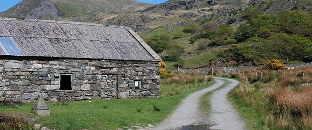 Lane to Graig-Isa farm Leaving the Nantcol road by Cil Cychwyn farmstead. The patch of green in the foreground used to be a useful parking spot for those heading for Rhinog Fach via the lane; now the notice placed in the window appears to discourage it.