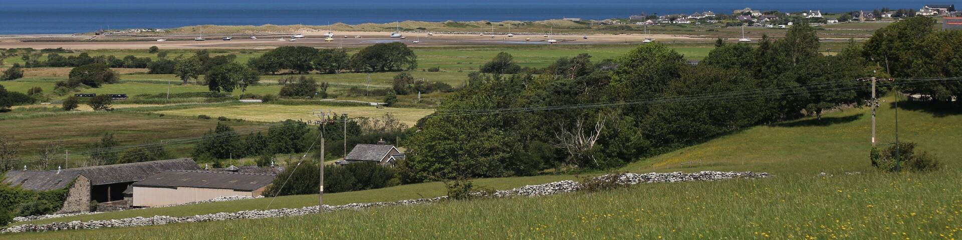 A coastal landscape with mountains, a body of water, and a small settlement.