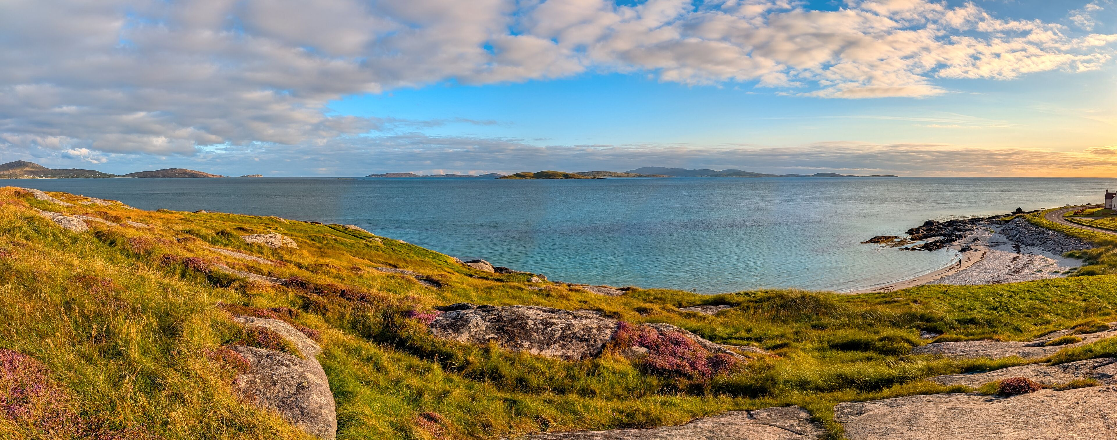Karibik-Feeling auf South Uist – türkisblaues Panorama in den Äußeren Hebriden, Schottland -Küstenlandschaft mit türkisblauem Wasser, violetter Besenheide und Sandbucht. Sommerliche Ruhe und Fernweh.