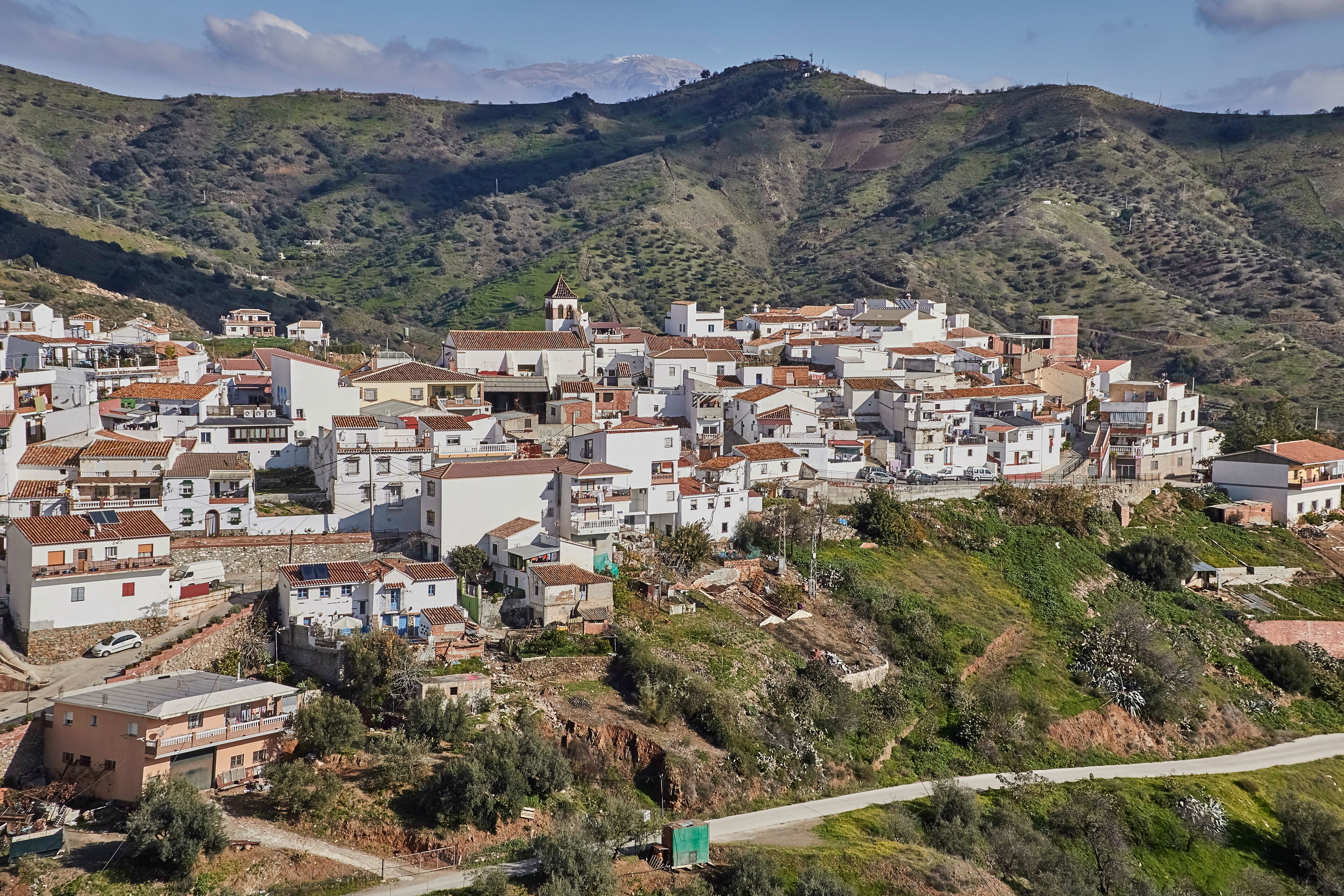A hillside village with white buildings and terracotta roofs.