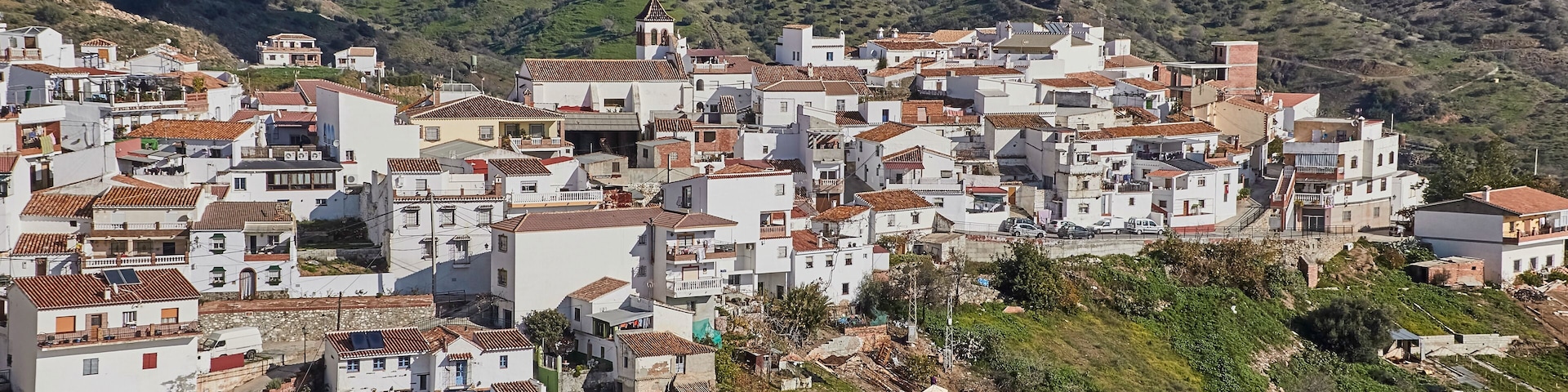 A hillside village with white buildings and terracotta roofs.