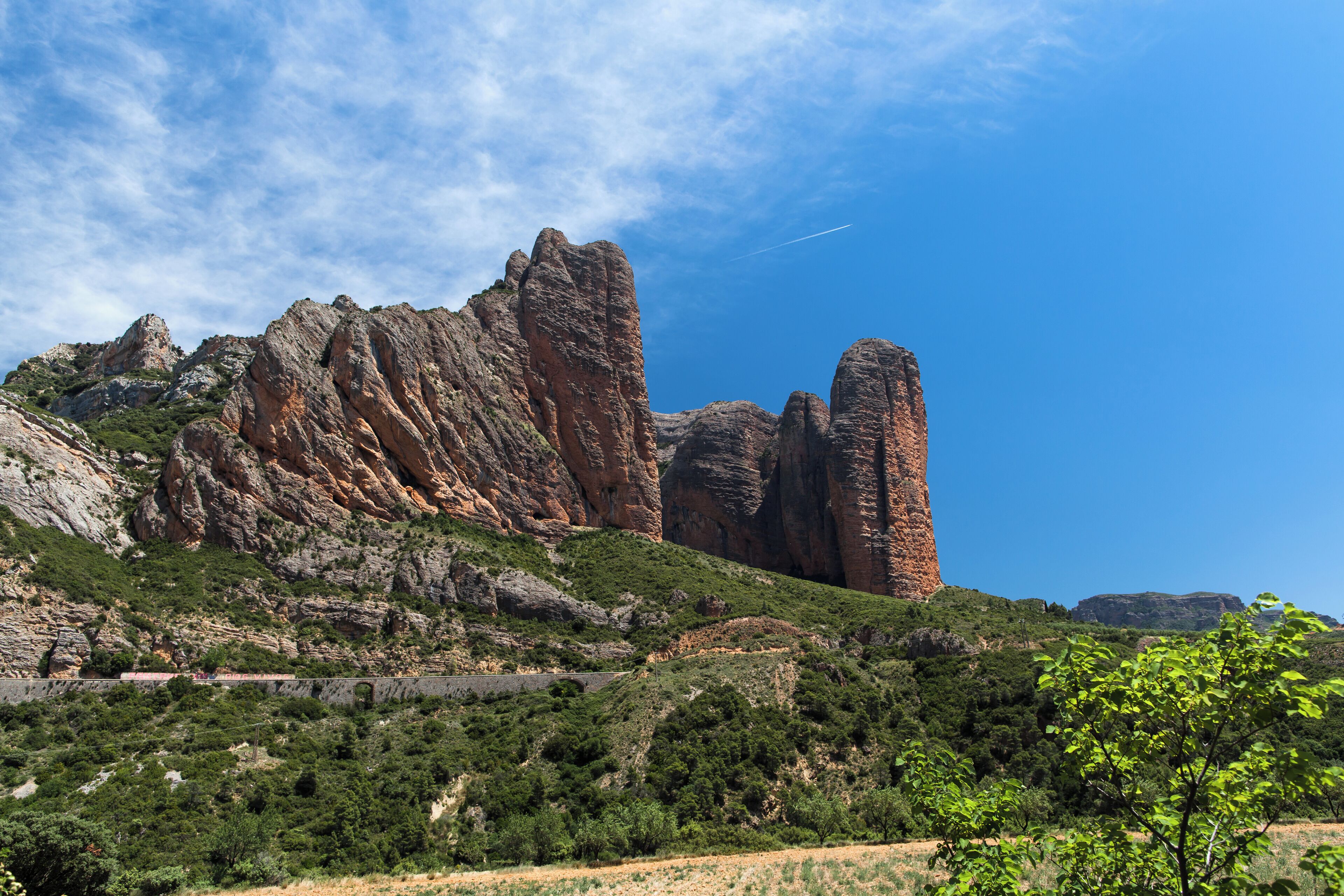A mountainous landscape with prominent rock formations and a clear blue sky.