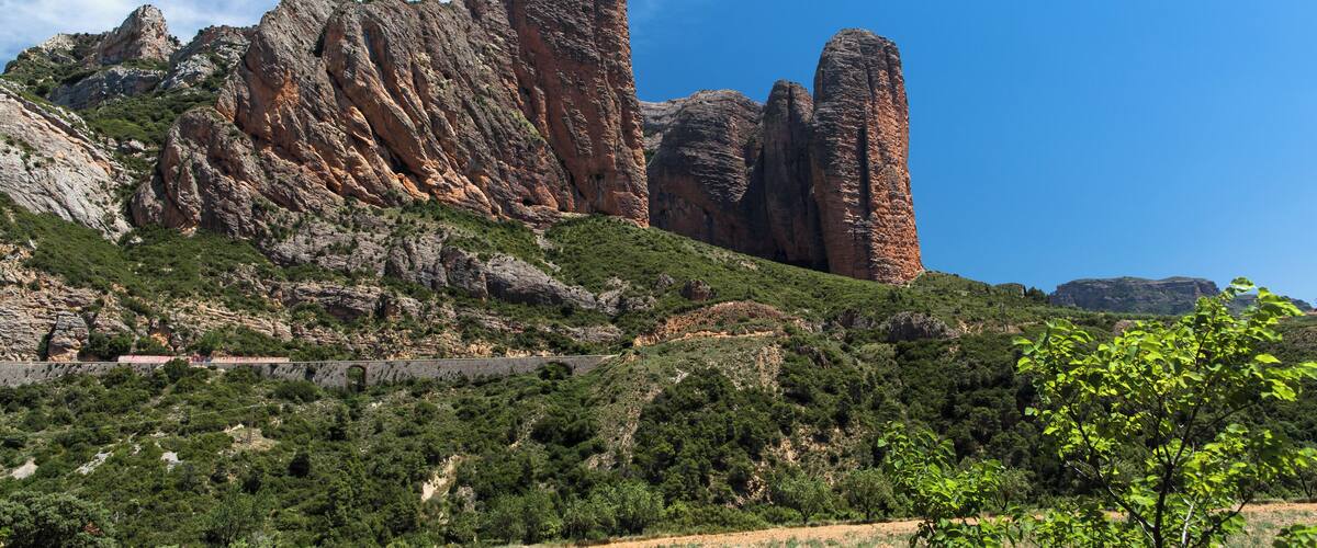 A mountainous landscape with prominent rock formations and a clear blue sky.