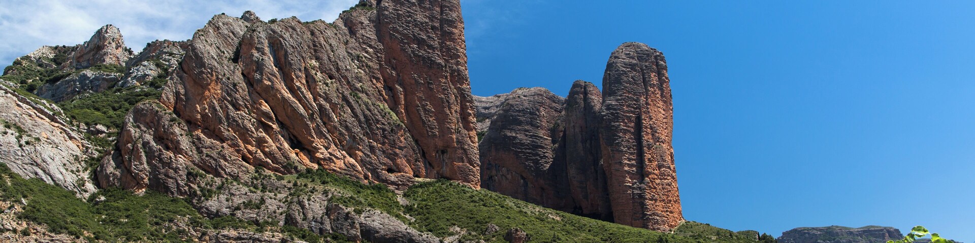 A mountainous landscape with prominent rock formations and a clear blue sky.
