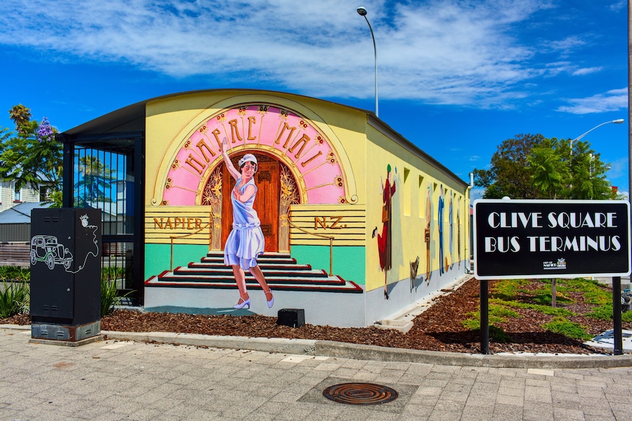 A colorful building with a mural of a woman in a dress, labeled "NAPIER" and "CLIVE SQUARE BUS TERMINUS".
