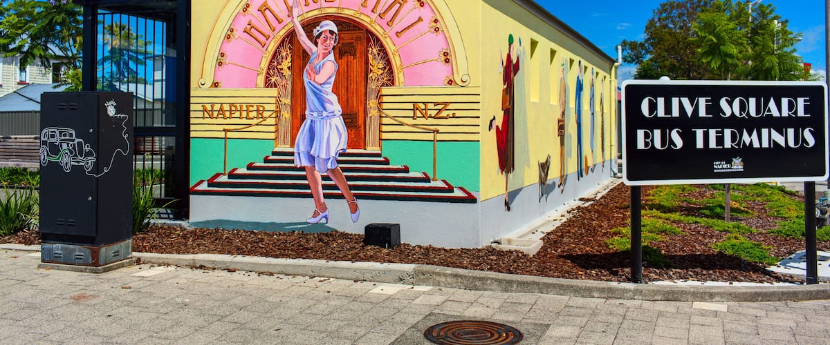 A colorful building with a mural of a woman in a dress, labeled "NAPIER" and "CLIVE SQUARE BUS TERMINUS".