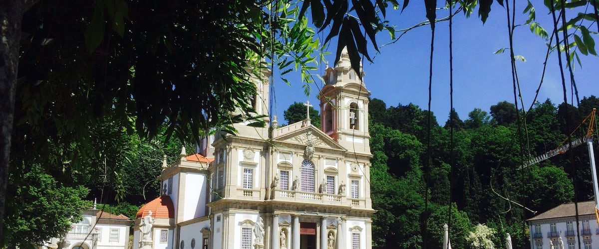 A historic building with a bell tower, surrounded by lush greenery and a well-maintained garden.