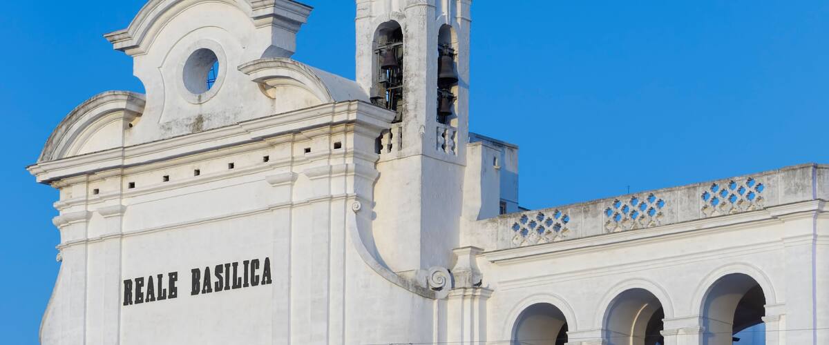 A white church with the inscription "REALE BASILICA" and a bell tower.