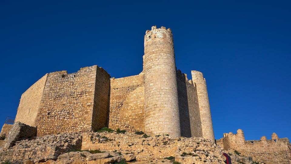 A historic stone castle with a prominent central tower and surrounding walls.
