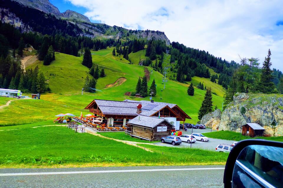 A mountain lodge with a ski lift, surrounded by lush green hills and rocky mountains.