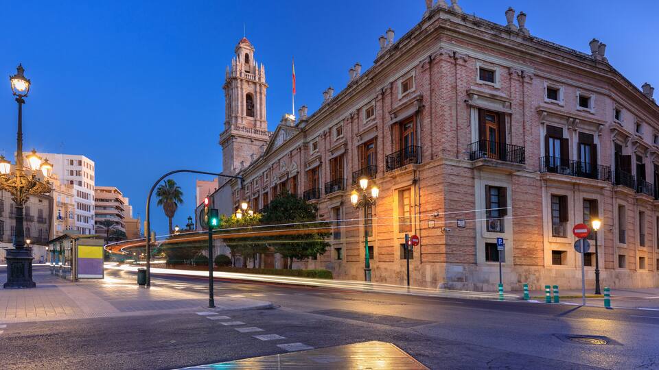 A historic building with a clock tower, street lamps, and a tram.