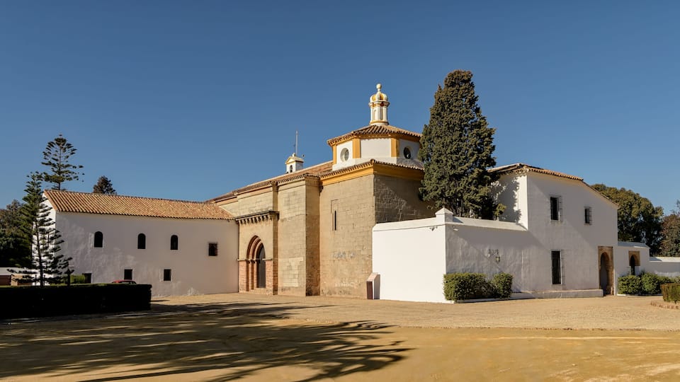 A historic church with a bell tower, surrounded by trees and a clear sky.