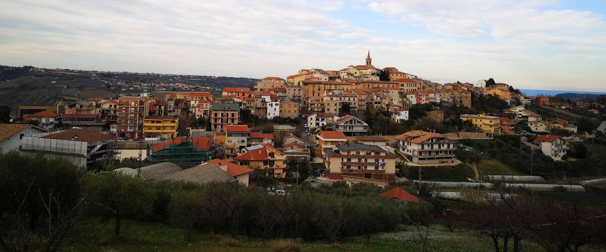 A town with colorful buildings, a prominent church, and rolling hills in the background.