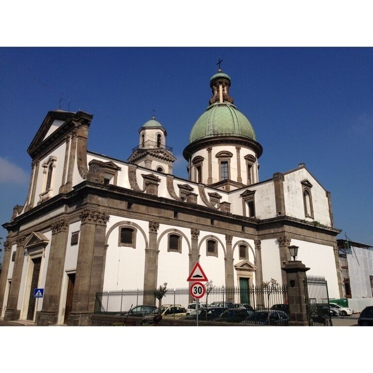 A historic church with two domes, a clock tower, and a speed limit sign.
