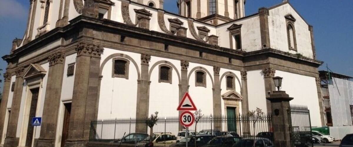 A historic church with two domes, a clock tower, and a speed limit sign.